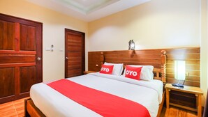 A hotel room with a large bed, wooden headboard, and a nightstand with a lamp. - OYO 690 Bann Supansa Resort (Krabi)