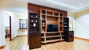 A spacious room with a wooden entertainment unit, a flat-screen TV, and a large mirror. - OYO 690 Bann Supansa Resort (Krabi)