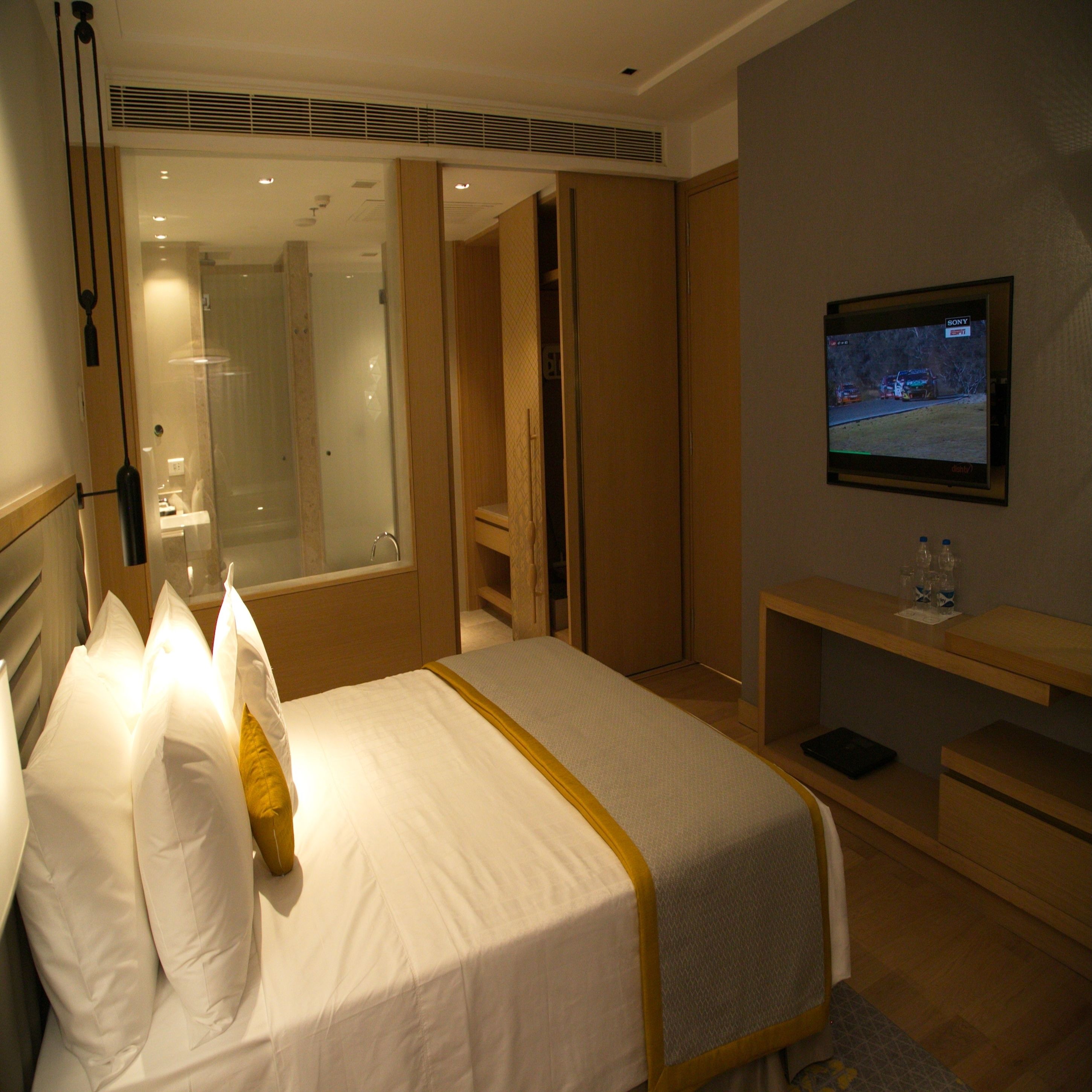 A hotel room with a bed, a TV, a desk, and a mirror.