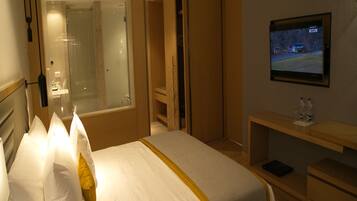 Una habitación de hotel con cama, televisión, escritorio y espejo.