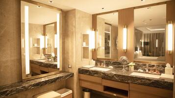 Un baño moderno con un espejo grande, encimera de mármol y mueble de tocador de madera.