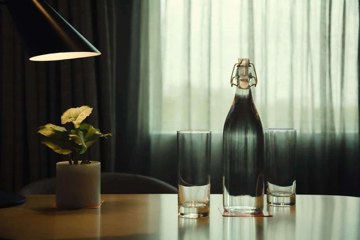 Een tafel met een kaars, een fles en twee glazen.