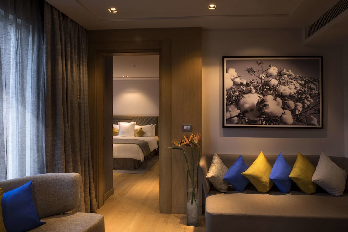 Een hotelkamer met een bed, een slaapbank, een bijzettafeltje en een schilderij aan de muur.