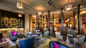 A modern lobby with a bar area, seating arrangements, and decorative lighting.
