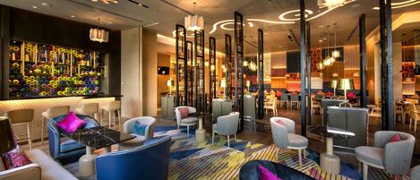 A modern lobby with a bar area, seating arrangements, and decorative lighting.