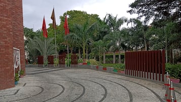 A paved entrance area with a brick wall, red flags, and potted plants.