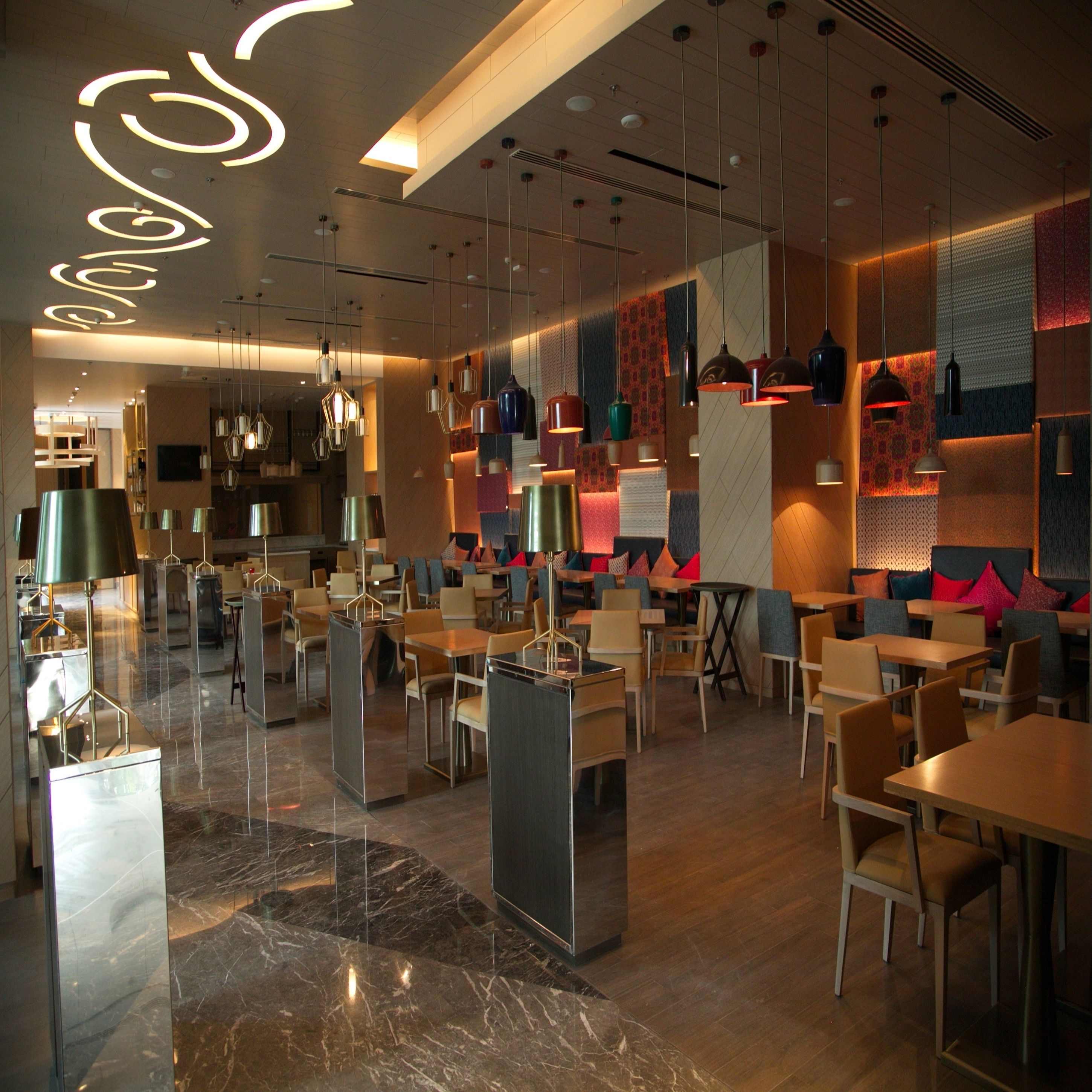 A modern restaurant interior with marble flooring, multiple dining areas, and contemporary lighting fixtures.
