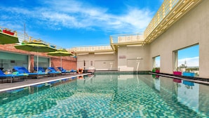 A swimming pool with checkered tiles, lounge chairs, and umbrellas.