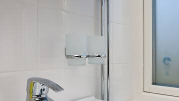 A modern bathroom with a chrome faucet, a glass shower enclosure, and a white bathtub.