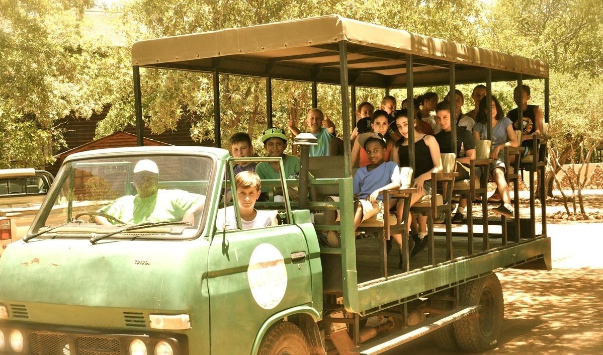 A green vehicle with a covered top carrying passengers.