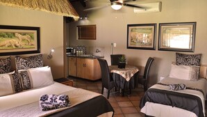 Une chambre d’hôtel avec deux lits, une kitchenette, un coin repas et des œuvres d’art aux murs.