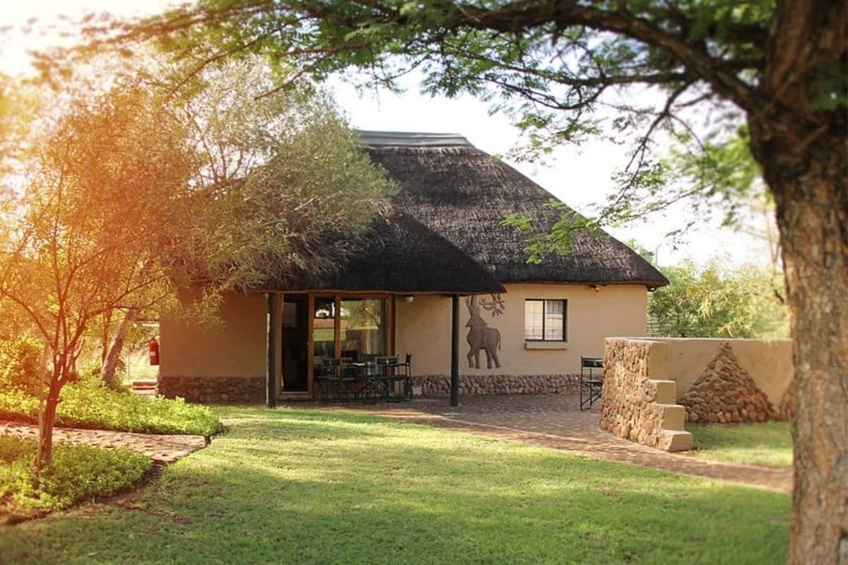 A thatched-roof building with a patio area, a dining table, and chairs.
