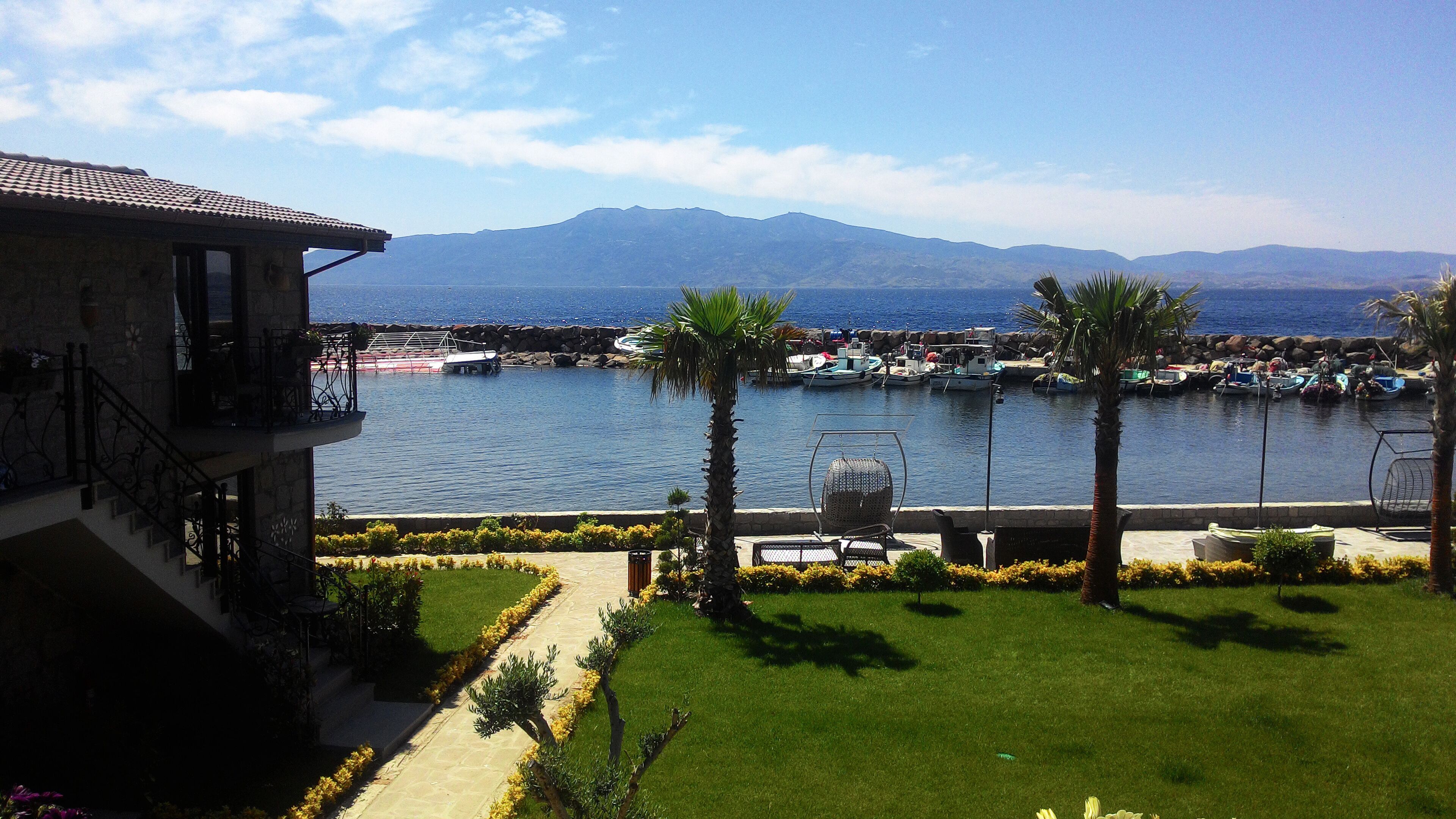 A view of a marina with boats, a mountain in the background, and a building with a balcony overlooking the water.
