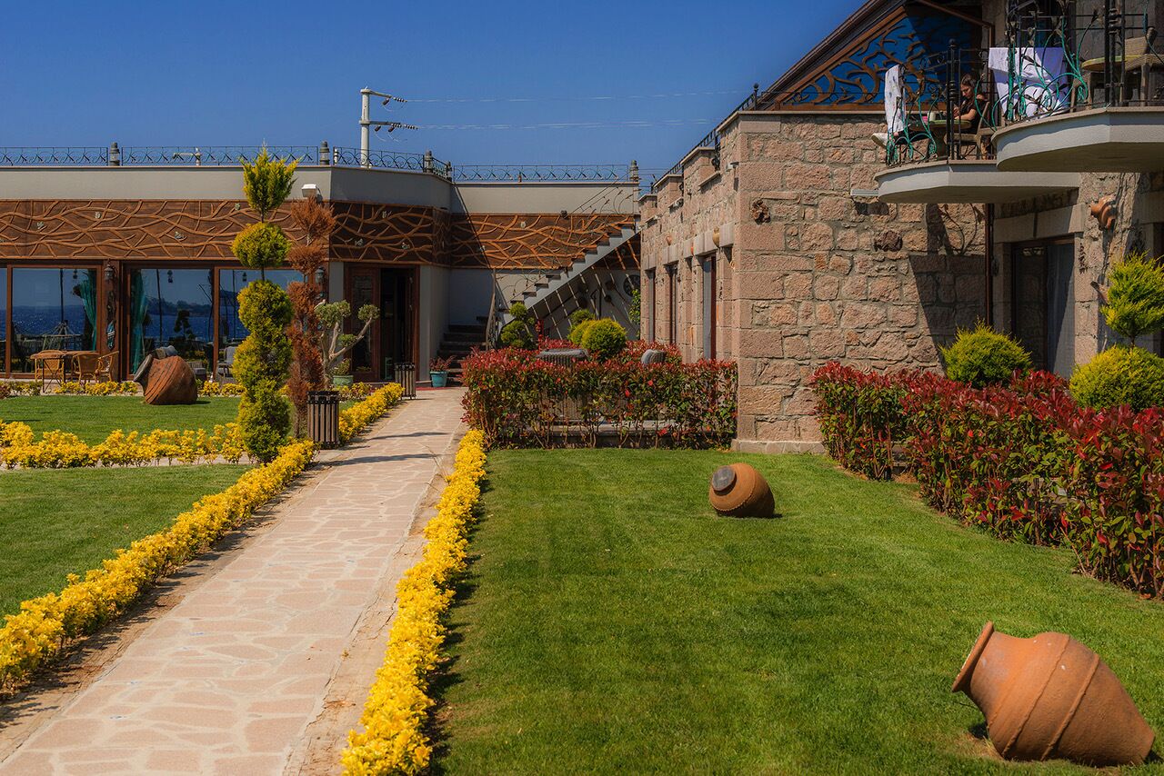 Un edificio moderno con fachada de piedra, entrada de cristal y un jardín cuidado con flores amarillas y un sendero de piedra.
