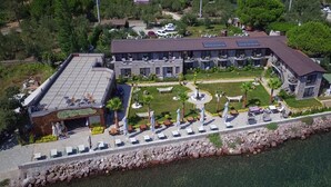 An aerial view of a hotel with a rooftop restaurant, a swimming pool, and a landscaped garden.