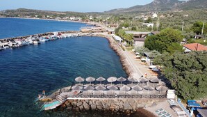 A coastal area with a pier, boats, and a beach with umbrellas.