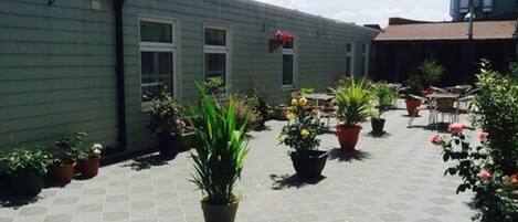 A rooftop patio with potted plants and outdoor seating.