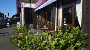 A storefront with outdoor seating, potted plants, and a clear blue sky. - Star Anglia Hotel (Colchester)