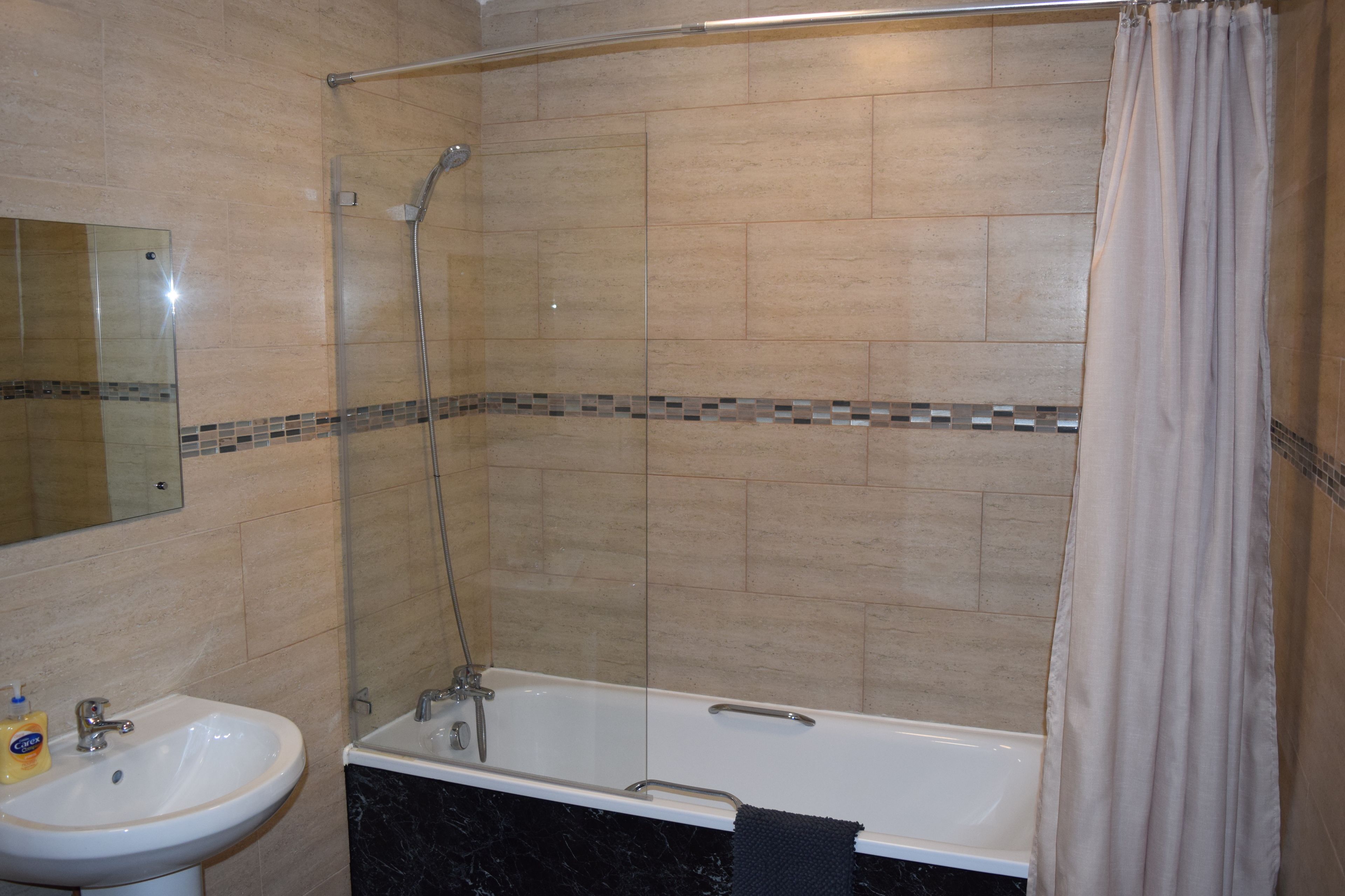Un baño con bañera, ducha y lavamanos.