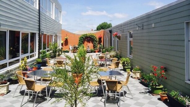 An outdoor patio area with tables and chairs, surrounded by potted plants and a brick wall. - Star Anglia Hotel (Colchester)