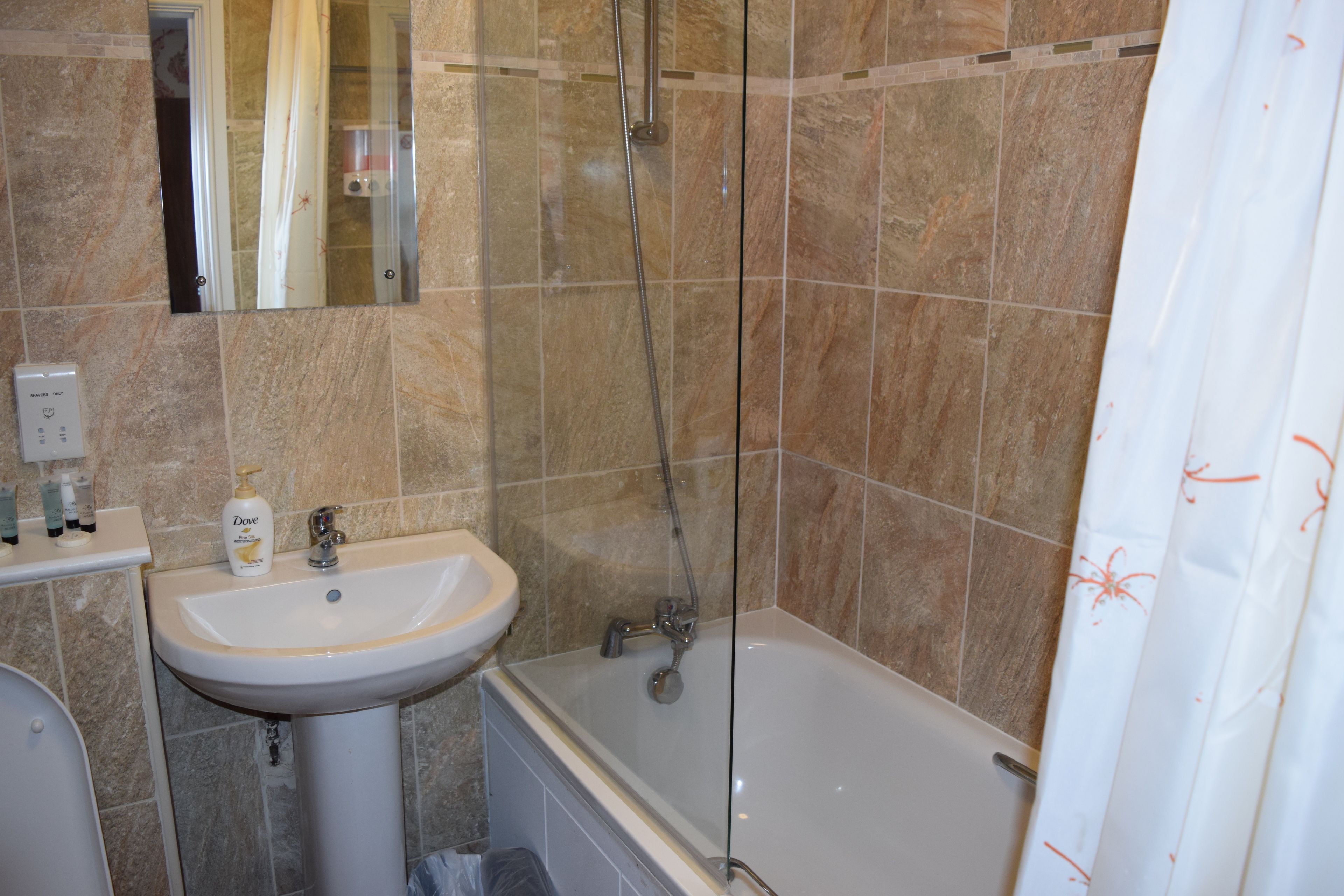 A bathroom with a sink, mirror, shower, and bathtub.