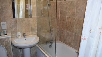 A bathroom with a sink, mirror, shower, and bathtub.