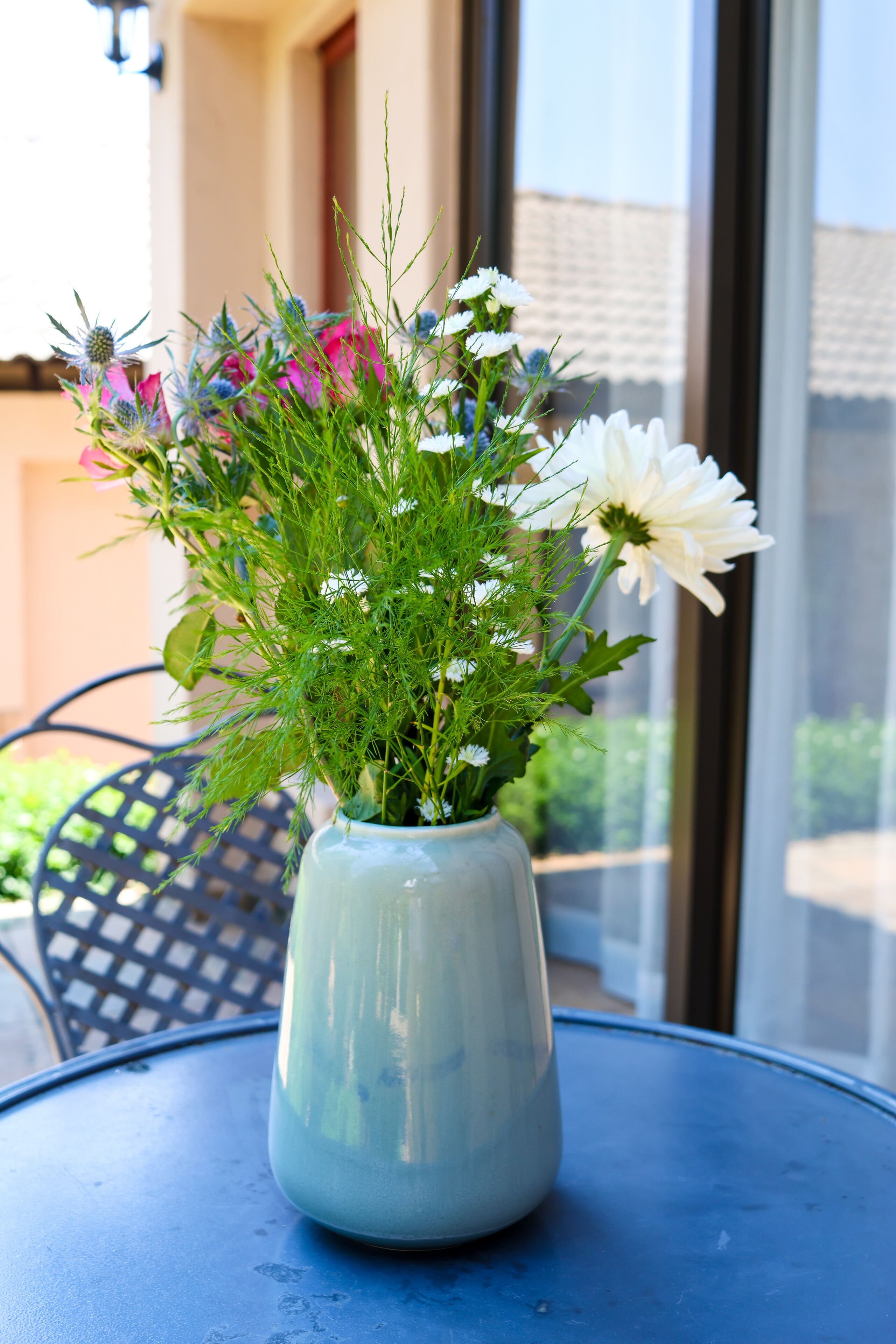 A vase with flowers on a blue table.