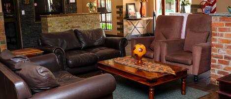A cozy living room with leather sofas, a wooden coffee table, and a brick fireplace.