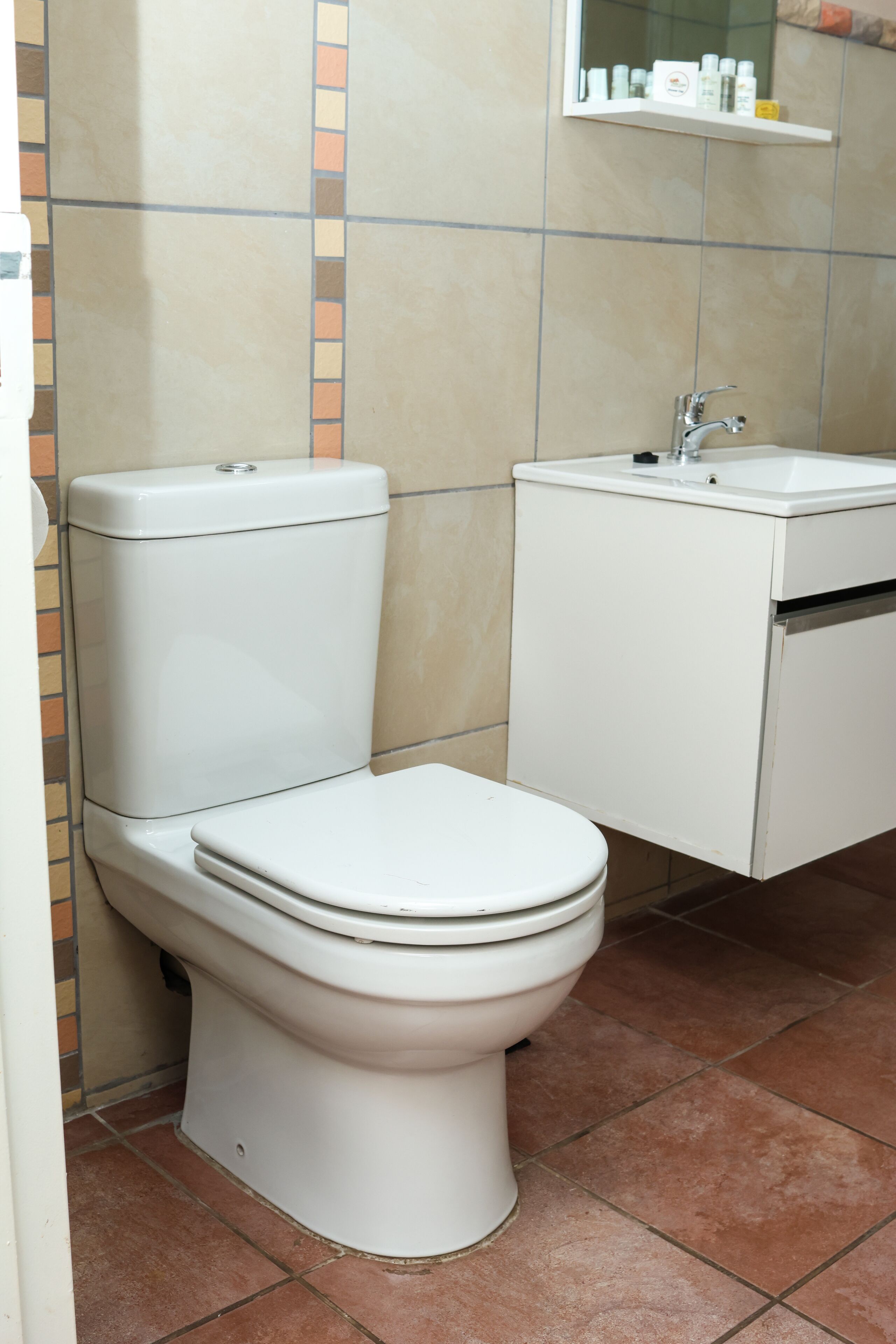 A bathroom with a toilet, sink, and tiled walls.