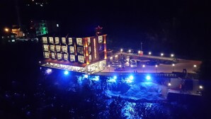 A multi-story building with a restaurant on the ground floor, situated by a waterfront with illuminated blue lights. - Ayder Hanedan Hotel (Ardesen)