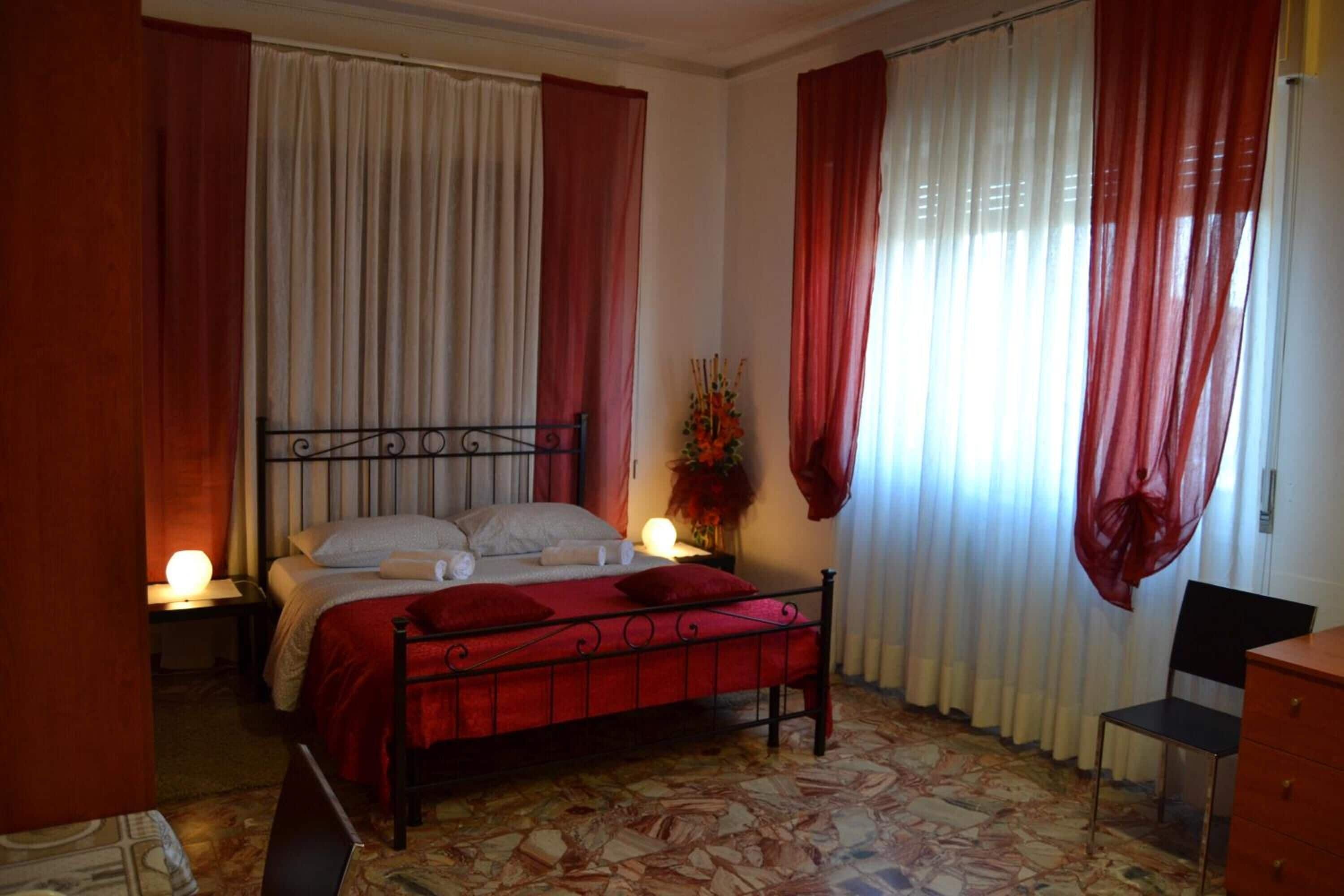 Un dormitorio con cama, cortinas, mesita de noche, silla y cómoda.