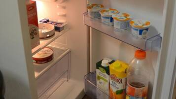 A refrigerator with multiple shelves, containing various food items and beverages.