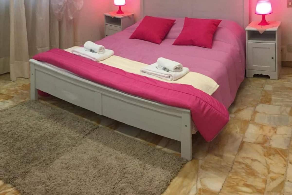 Quarto com cama, duas mesas de cabeceira, cabeceira e tapete.