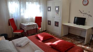 Une chambre d’hôtel équipée d’un lit, d’un bureau, d’une télévision et d’une armoire.