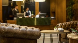 A lobby with a reception desk, leather seating, and pendant lighting. - Vista Hotel (Mezitli)