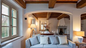 A living room with a sofa, a fireplace, and a dining area. - Luxury Tuscany Villa with Private Pool, 13 Sleeps. Lucca 10 km. (San Ginese Di Compito Lucca)