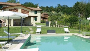 A swimming pool with lounge chairs and umbrellas, a building with a tiled roof, and a grassy area with trees in the background. - Luxury Tuscany Villa with Private Pool, 13 Sleeps. Lucca 10 km. (San Ginese Di Compito Lucca)