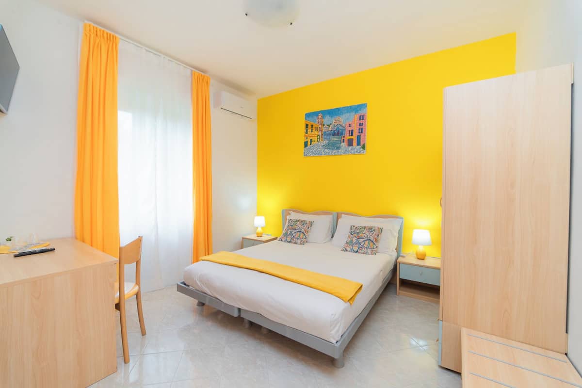 A hotel room with a bed, bedside tables, a desk, and a chair.
