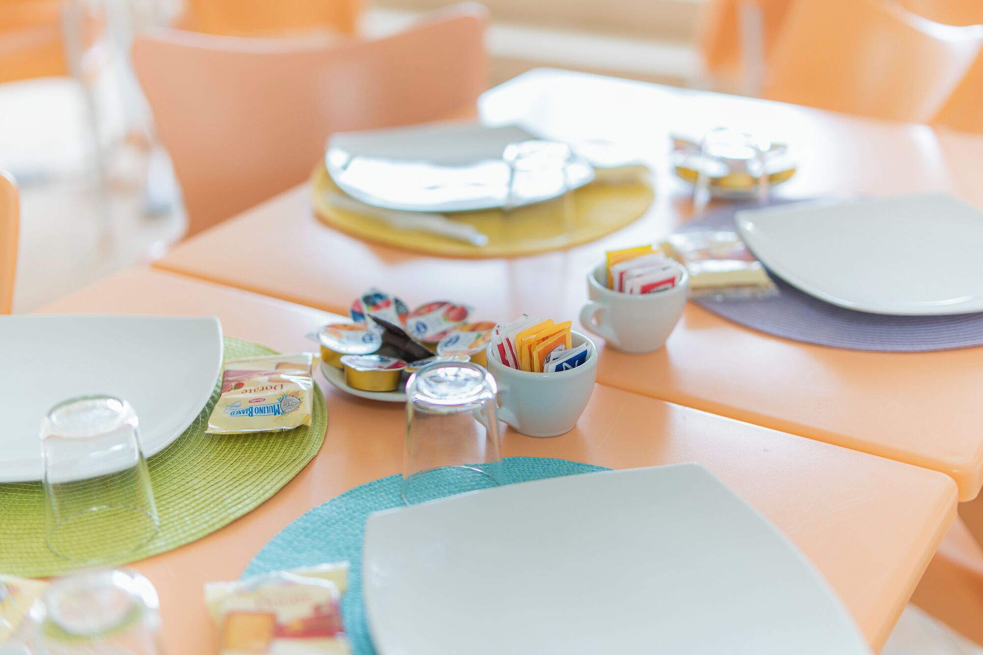 Una mesa dispuesta con platos, vasos y un recipiente con aperitivos.