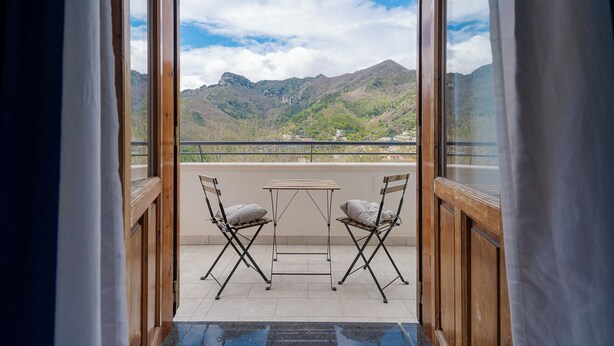 A balcony with a table and two chairs, overlooking a mountainous landscape. - Tra i Monti (Tramonti)