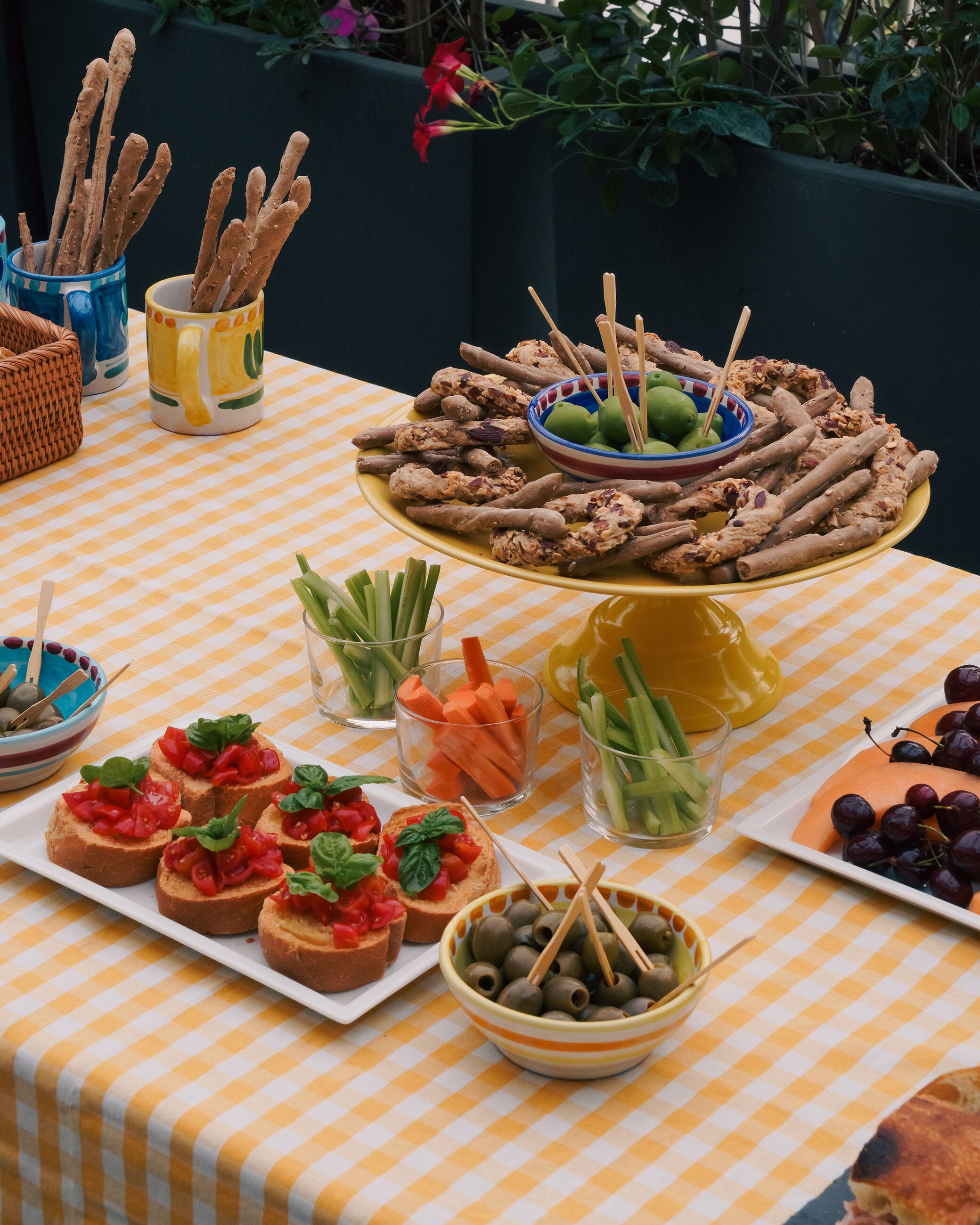 Uma mesa de buffet com diversos alimentos, incluindo palitos de pão, azeitonas e vegetais.