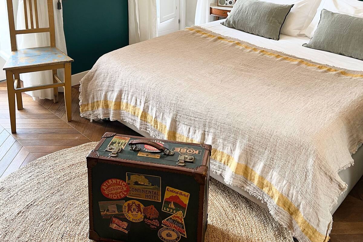 Ein Schlafzimmer mit einem großen Bett, einem Sessel, einem Koffer und einem an der Wand befestigten Radio.