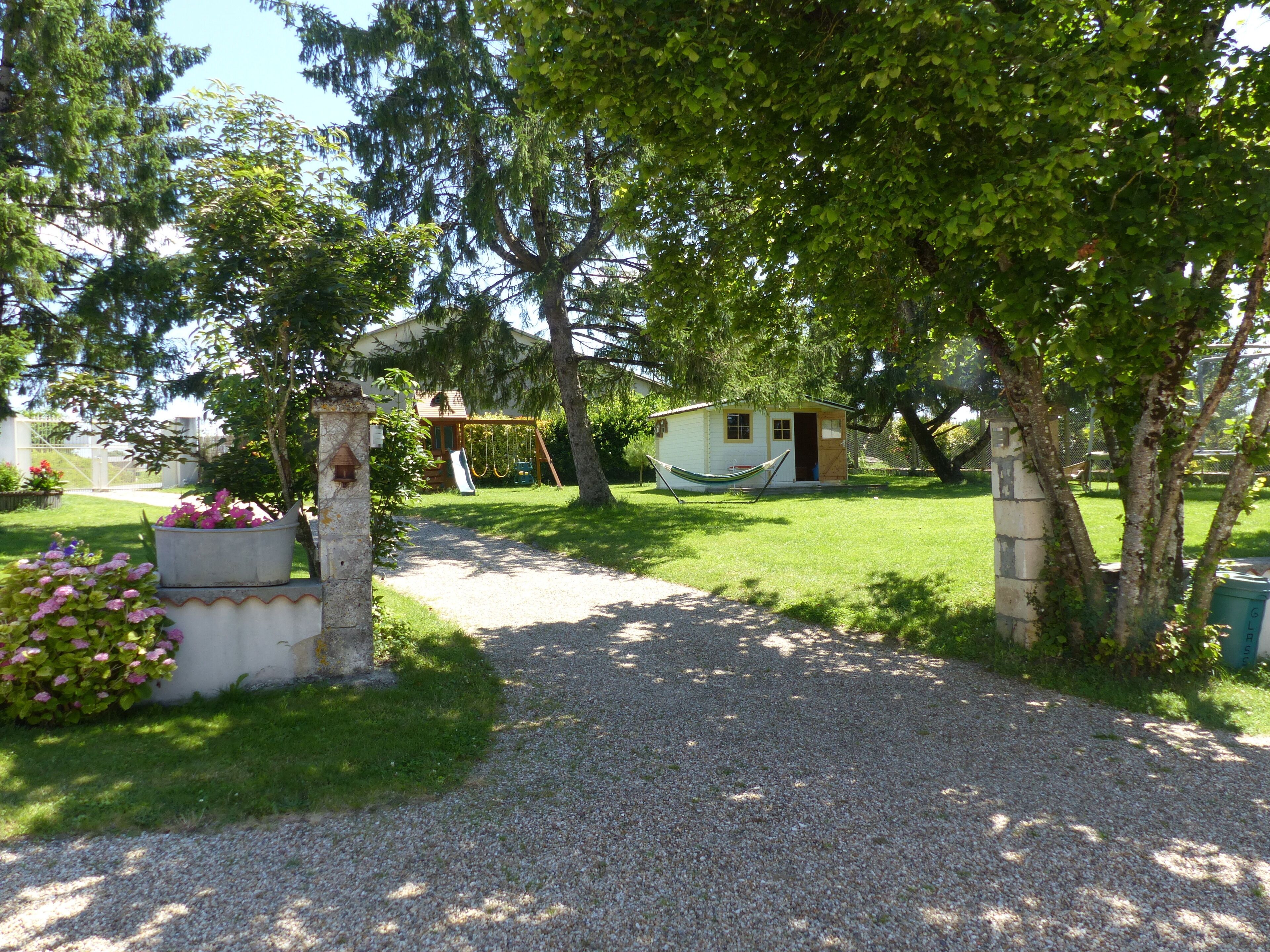 Ein Kiesweg führt zu einem kleinen Haus mit einer Veranda und einer Hängematte.