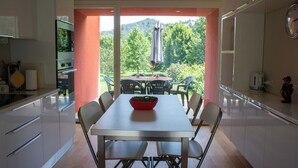 A modern kitchen with a dining area, large windows, and a view of greenery. - BRIGHT AND REFINED VILLA WITH POOL IMMERSED IN THE GREEN OF THE HILLS OF LUCCA (LUCCA)