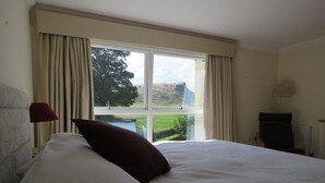 Habitación de hotel con una cama grande, vistas al exterior y un escritorio con lámpara.