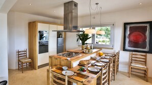 A modern kitchen with a central island, built-in oven, and stainless steel range hood.
