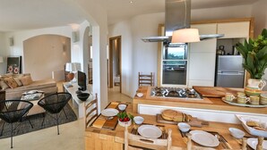 A modern kitchen with a central island, a dining area with a sofa and chairs, and a view of the outdoors.