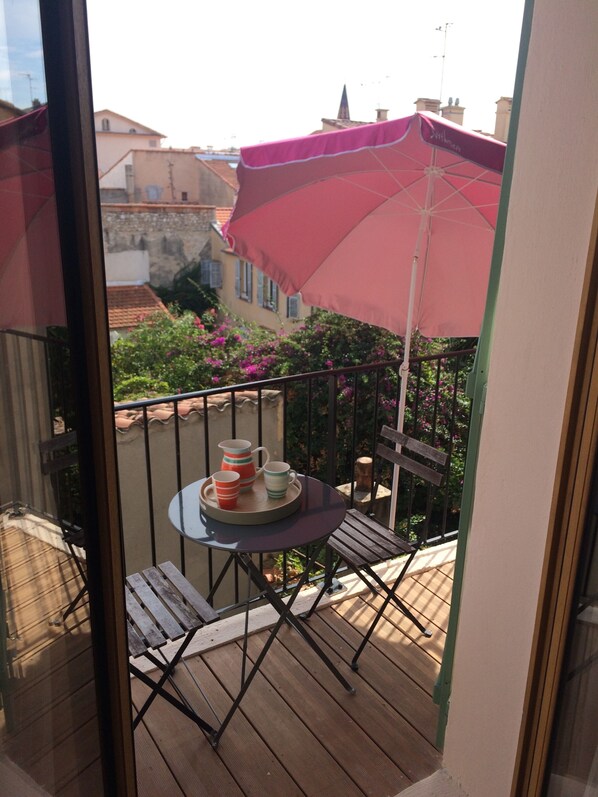 A balcony with a table, chairs, and a red umbrella. - 20m2 fully renovated Studio with Private Balcony, rates are All Inclusive. (Antibes)