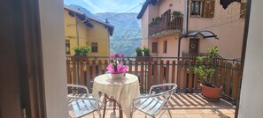A balcony with a table, chairs, potted plants, and a view of a mountain. - CHALET WITH POOL FOR 2 PEOPLE IN VALLEY ALBANO (Garzeno)