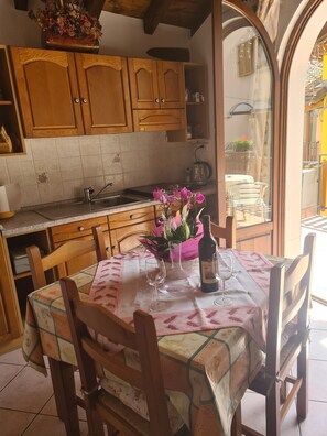 A kitchen with wooden cabinets, a tiled backsplash, a dining table with chairs, and a window overlooking a balcony.